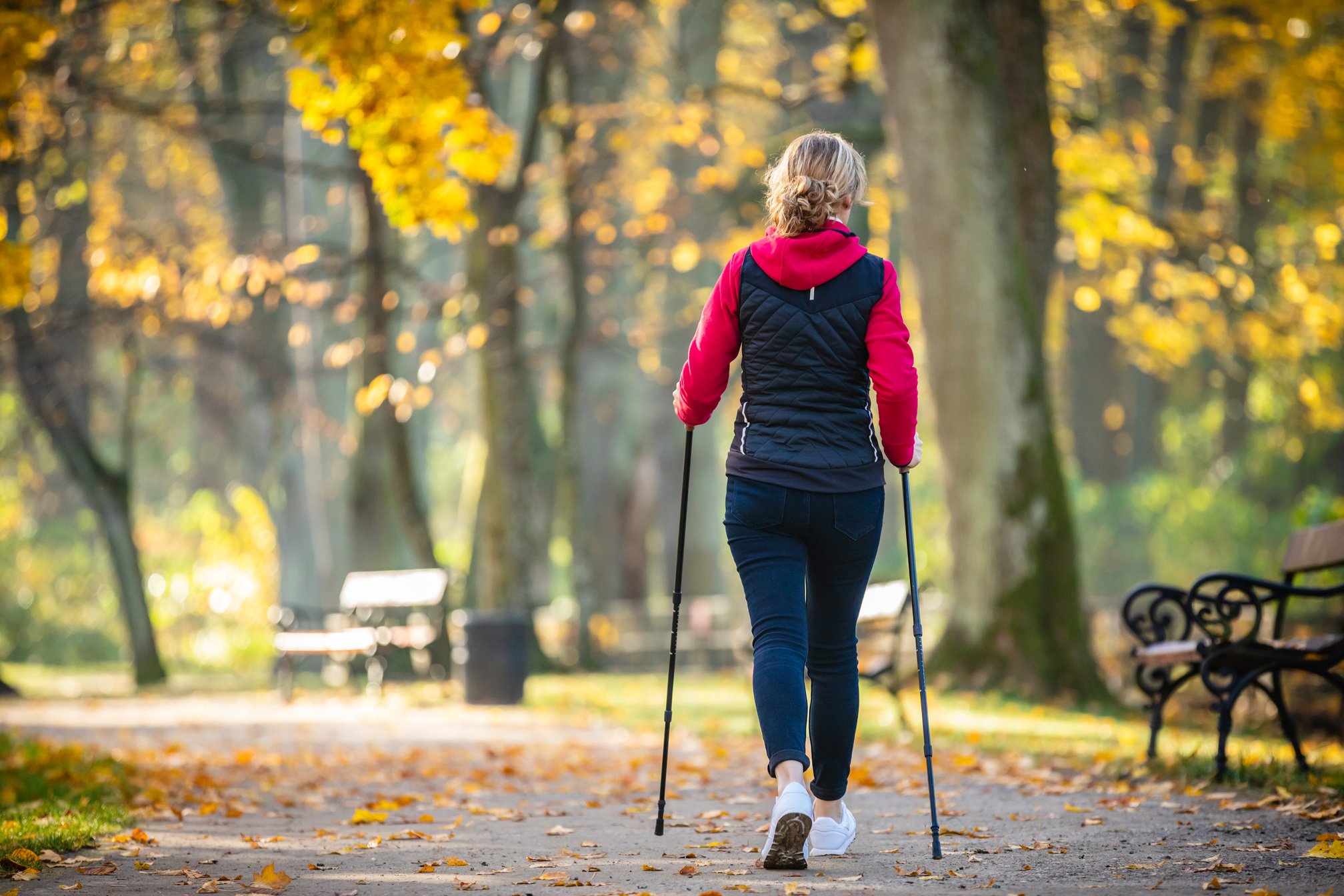 Mid aged woman nordic walking in city park